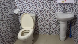Une salle de bain avec des toilettes, un lavabo et une douche.