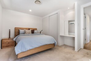 A bedroom with a bed, nightstand, wardrobe, and a mirror. - Casa Fern (Lennox Head)