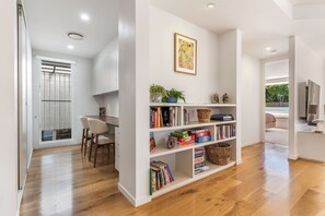 Un interior moderno con piso de madera, una estantería y un comedor con sillas.