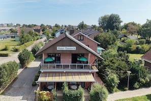 A two-story building with a sign reading 'Haus Tanneck.' It features a balcony with outdoor seating and a covered patio area. - Vrbo Property (Kellenhusen)