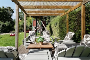 An outdoor seating area with a pergola, wooden chairs, a table, and a bottle of wine. - Vrbo Property (Kellenhusen)