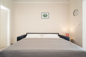 A bedroom with a bed, a nightstand, a wall clock, and a framed picture. - Vrbo Property (Kellenhusen)
