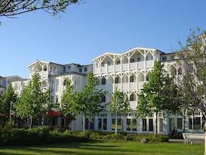 Ett hotell med flera våningar, vit fasad, stora fönster och en välskött gräsmatta.
