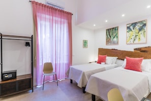 A hotel room with two beds, a chair, a desk with a computer, and artwork on the wall. - Mama Tita Rooms And Breakfast (Palermo)