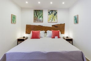 A hotel room with a large bed, two bedside tables, and three wall-mounted paintings. - Mama Tita Rooms And Breakfast (Palermo)