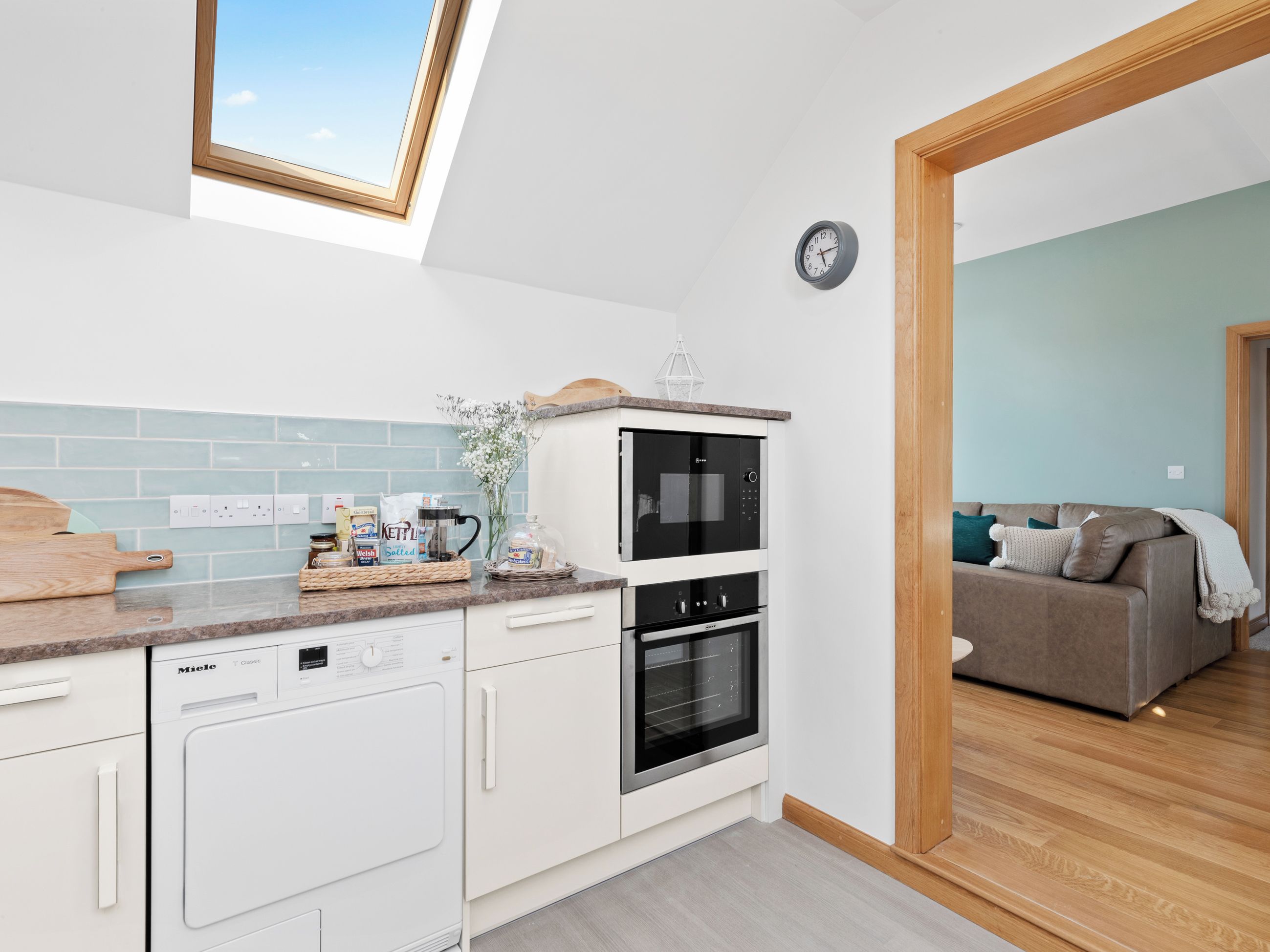 A modern kitchen with a dishwasher, oven, and a coffee maker on the counter.