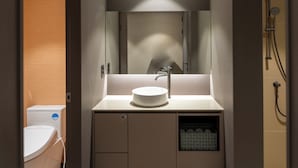 A modern bathroom with a round sink, a mirror, and a shower area. - Gray Hotel (Yongin)