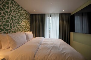 Una habitación de hotel con una cama, cortinas, una ventana y una pared con un diseño de hojas.