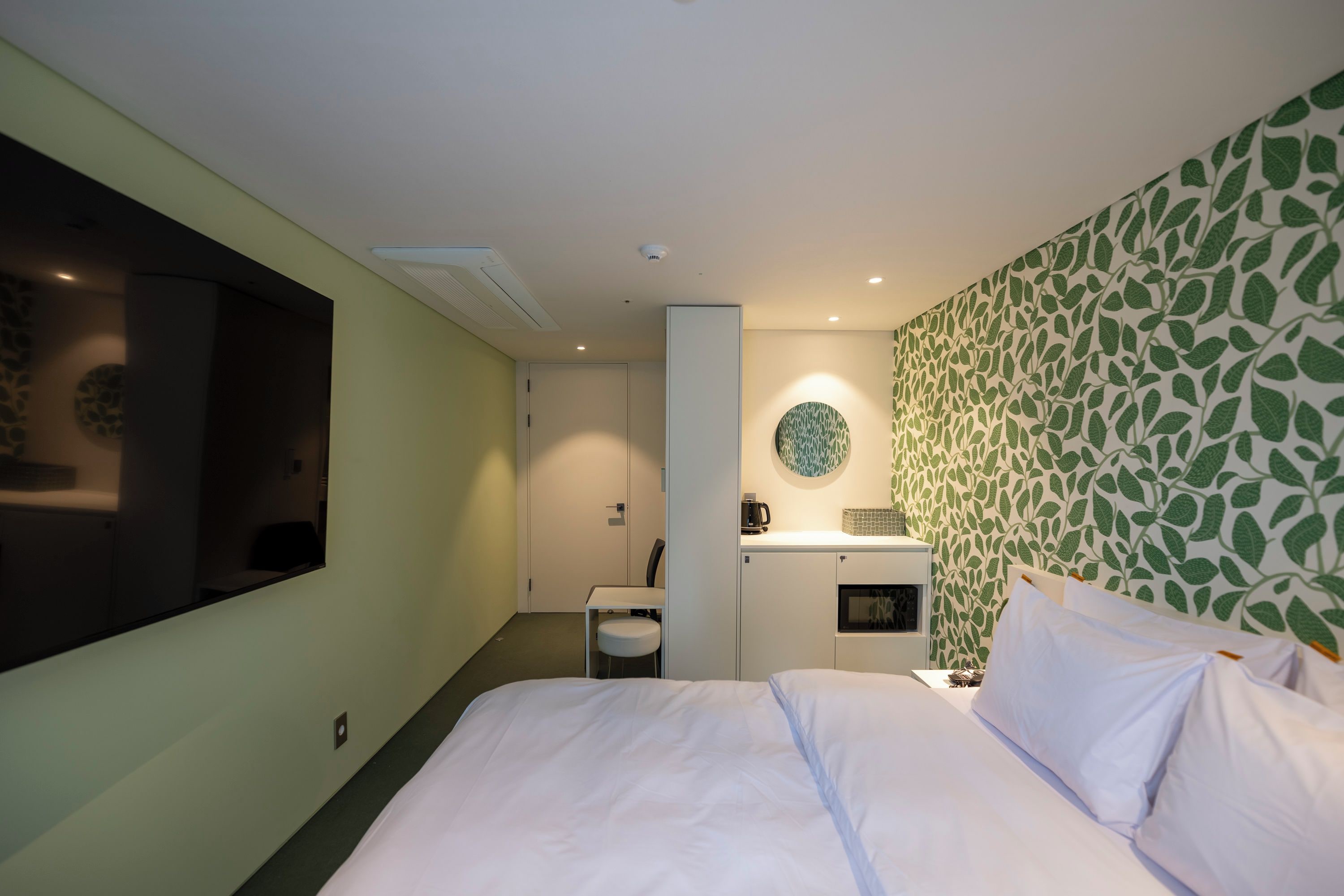 A hotel room with a bed, a desk, and a kitchenette.