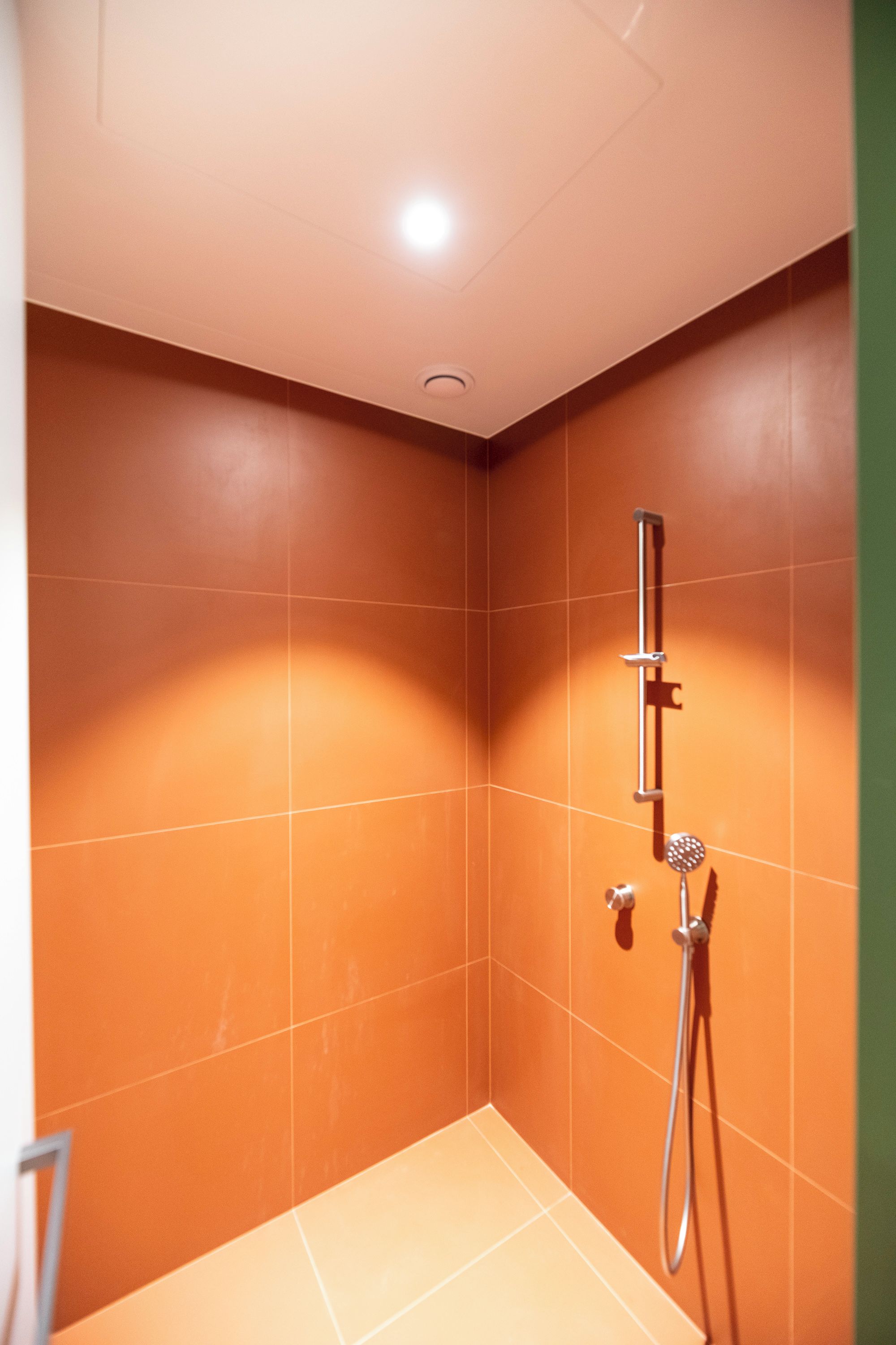 Un espacio de ducha pequeño y cerrado con un cabezal de ducha de mano y un grifo empotrado en la pared.