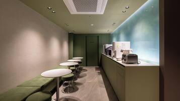 Un pasillo estrecho con asientos verdes, una kitchenette y una puerta que indica 'PERSONAL AUTORIZADO'.