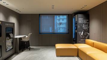 A modern interior with a sofa, a desk, a vending machine, and a projection screen.