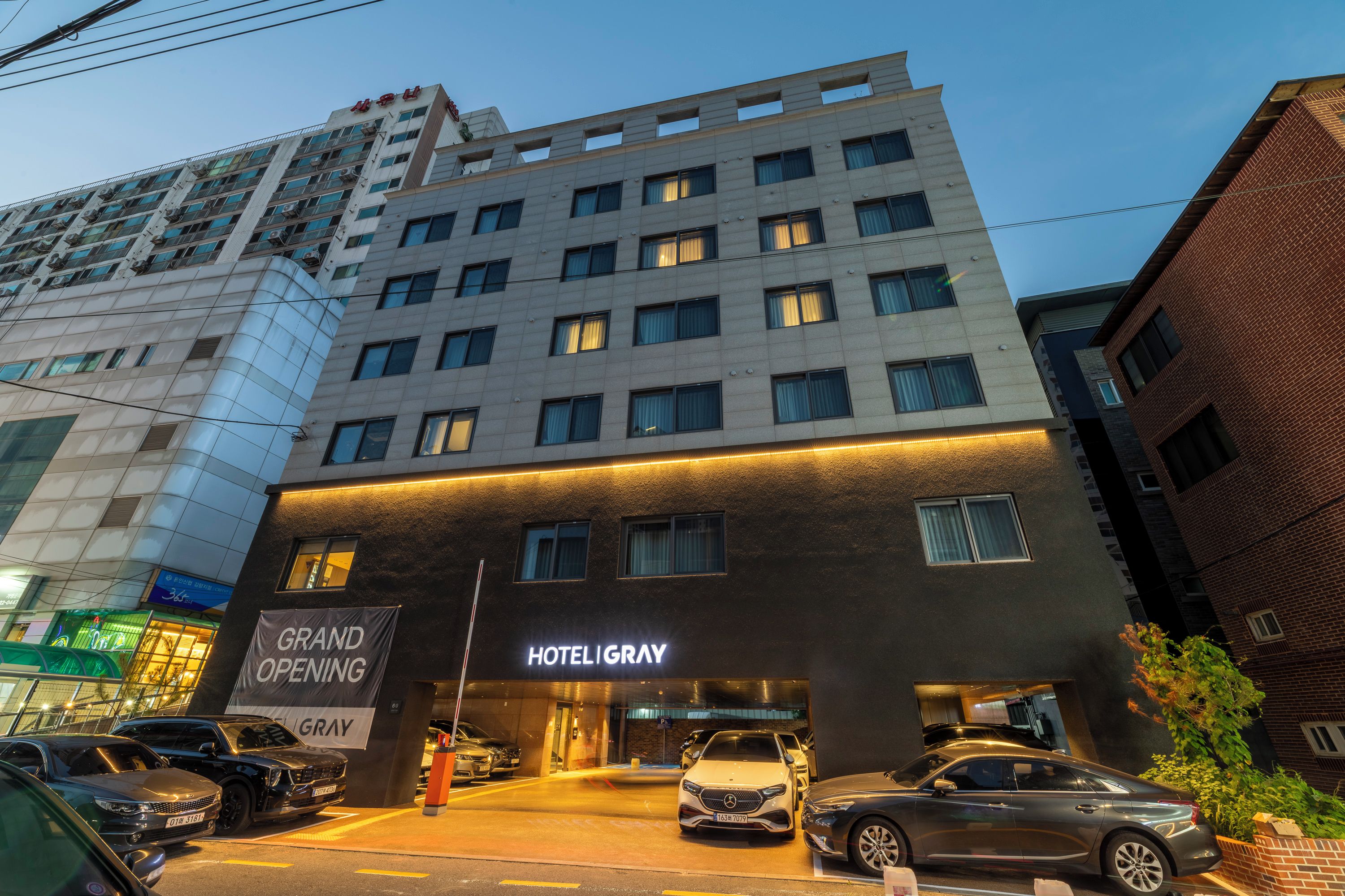 Un hotel con fachada moderna, varios pisos y una entrada destacada con un cartel que anuncia su inauguración.