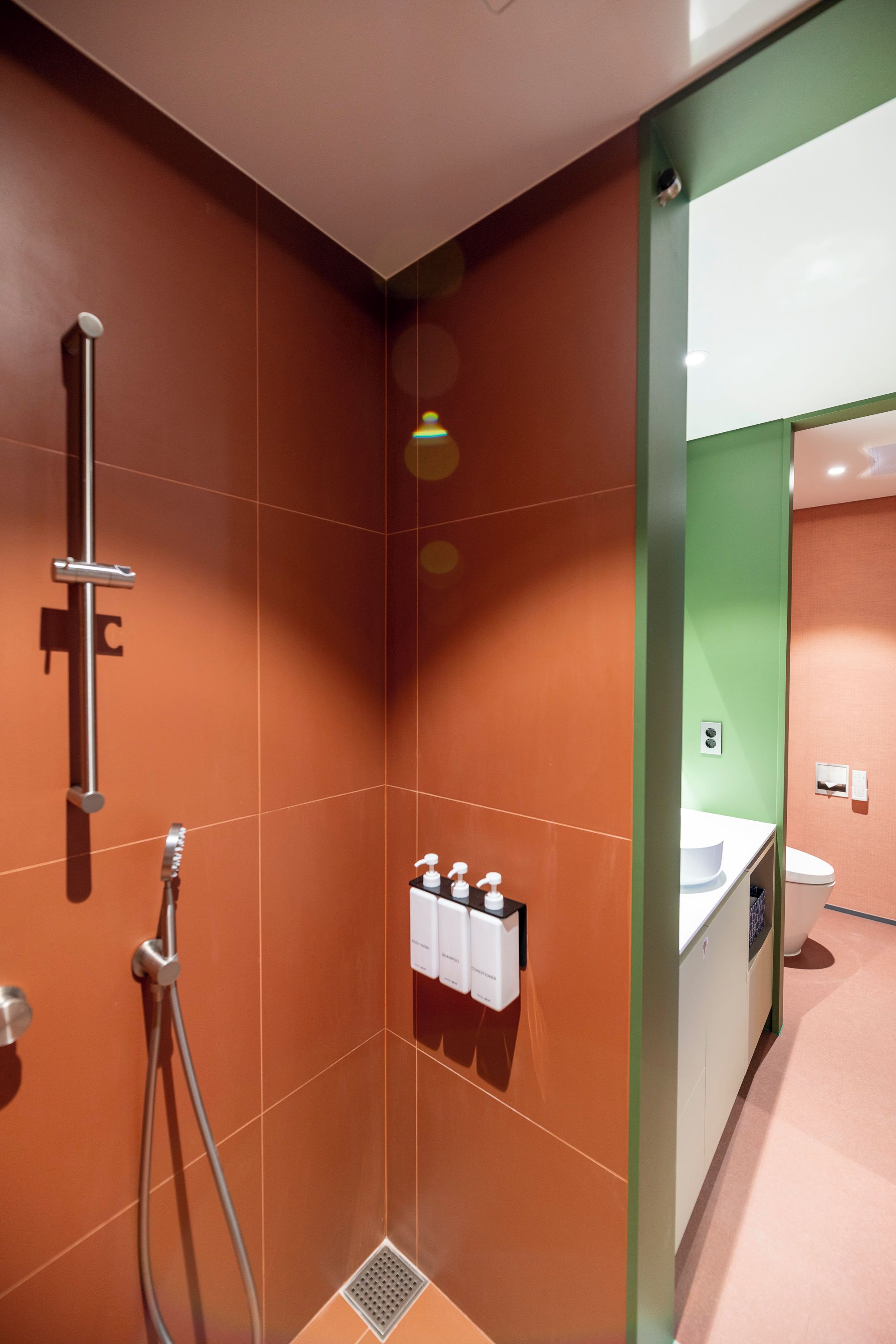 Een moderne badkamer met douche, toilet en wastafel.