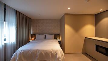 Habitación de hotel con una cama grande, un escritorio, un armario y una ventana con cortinas.
