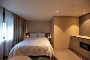 A hotel room with a large bed, a desk, a wardrobe, and a window with curtains. - Gray Hotel (Yongin-si)
