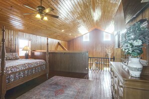 A wooden interior with a bed, a desk, and a staircase.