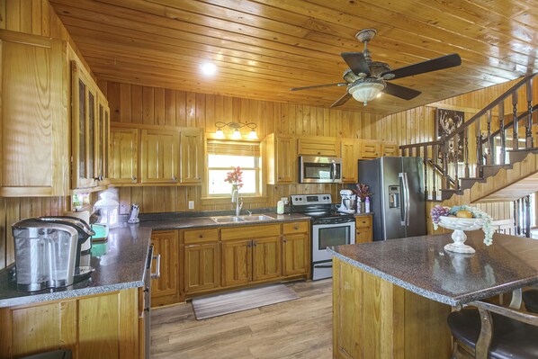 A wooden cabin interior with a kitchen featuring a stove, microwave, refrigerator, and wooden cabinets.
