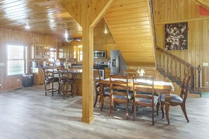 A spacious kitchen with wooden cabinets, a dining area with a large table and chairs, and a staircase leading to an upper level.