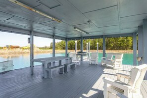 An outdoor covered deck with a pool, seating, and a view of the water.