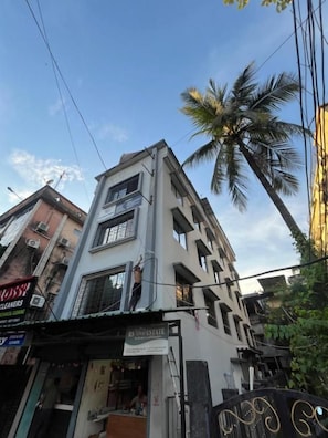A multi-story building with a commercial ground floor, including a shop with a sign that reads 'RS VIVE ESTATE.'