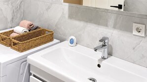Un baño con un lavamanos blanco, un espejo y una cesta de mimbre con toallas.