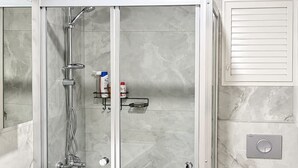 Un baño moderno con ducha de vidrio, inodoro y lavamanos.