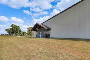 A building with a small attached structure, a grassy field, and a large white wall.