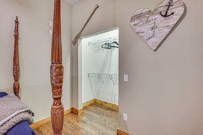 A bedroom with a wooden bed frame, a hanging clothes rack, and a heart-shaped wall decoration.