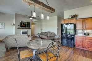 A modern kitchen with a refrigerator, wooden cabinets, and a dining area with a table and chairs.