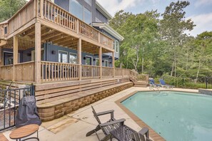 Eine zweistöckige Holzterrasse mit Pool, Liegestühlen und Grillplatz.