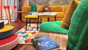 Een gezellige woonkamer met een bank, een bijzettafeltje en een wandprojector die een cirkelvormig beeld toont.