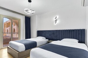 Habitación de hotel con dos camas, un ventanal con vista a un edificio y una lámpara moderna.