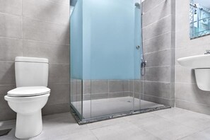 Un baño con inodoro, ducha acristalada y lavamanos.
