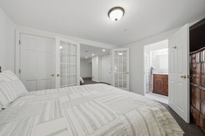 A bedroom with a bed, a wardrobe, and a bathroom visible through an open door. - Mountain-View Cedar Creek Condo w/ Trail Access (Conway)