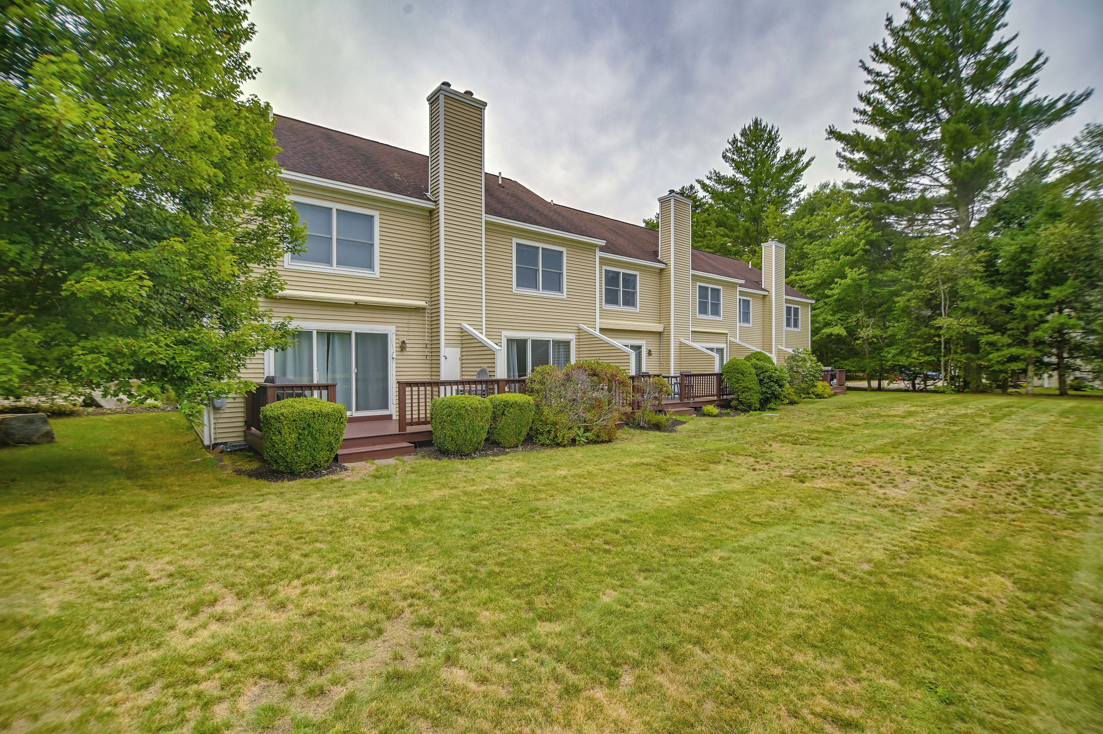 A two-story residential building with a front deck and a well-maintained lawn.