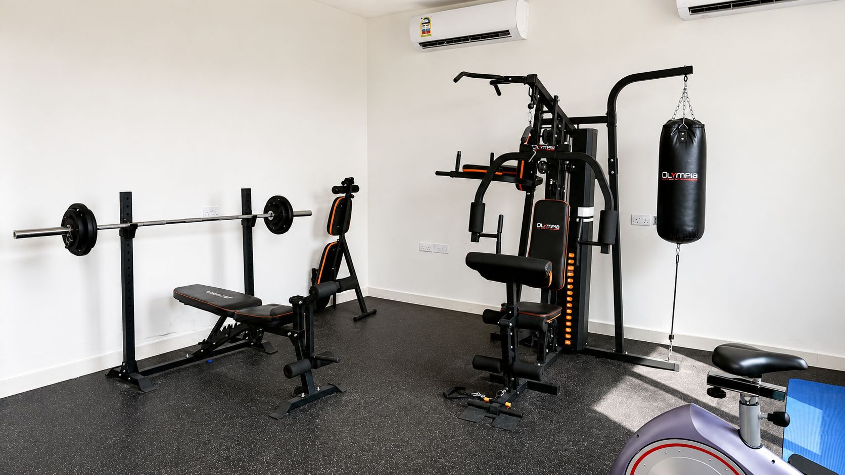 A gym with a bench press, squat rack, and a punching bag.