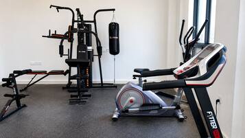 Un gimnasio con bicicleta estática, banco de pesas y saco de boxeo.