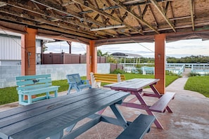 An outdoor covered picnic area with benches and picnic tables. - Boat Ramp, Fishing Pier & Game Room Retreat (Edgewater)