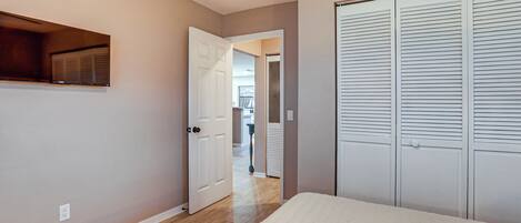 A hallway with a bed, a wardrobe, and a door leading to another room.