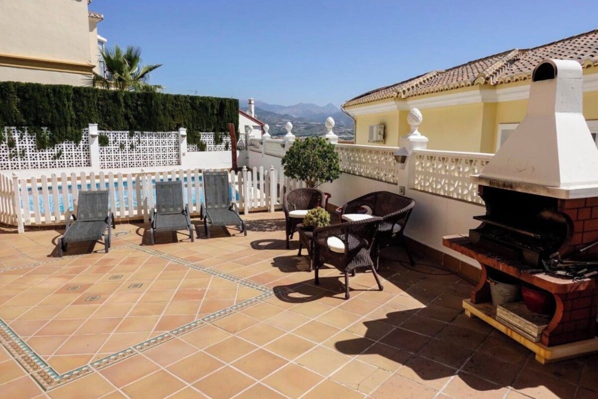 Un patio con mobiliario exterior, una parrilla y vistas a la ciudad.