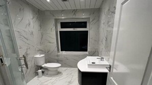 A bathroom with a toilet, a sink, and a shower. - Standard Triple Room - Shared (Manchester)