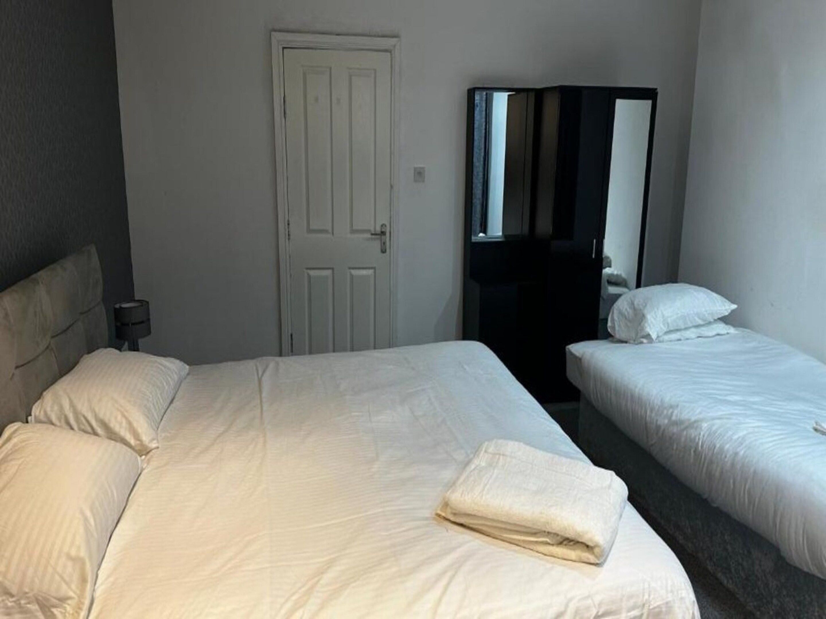 Habitación de hotel con dos camas, una puerta blanca y un espejo.