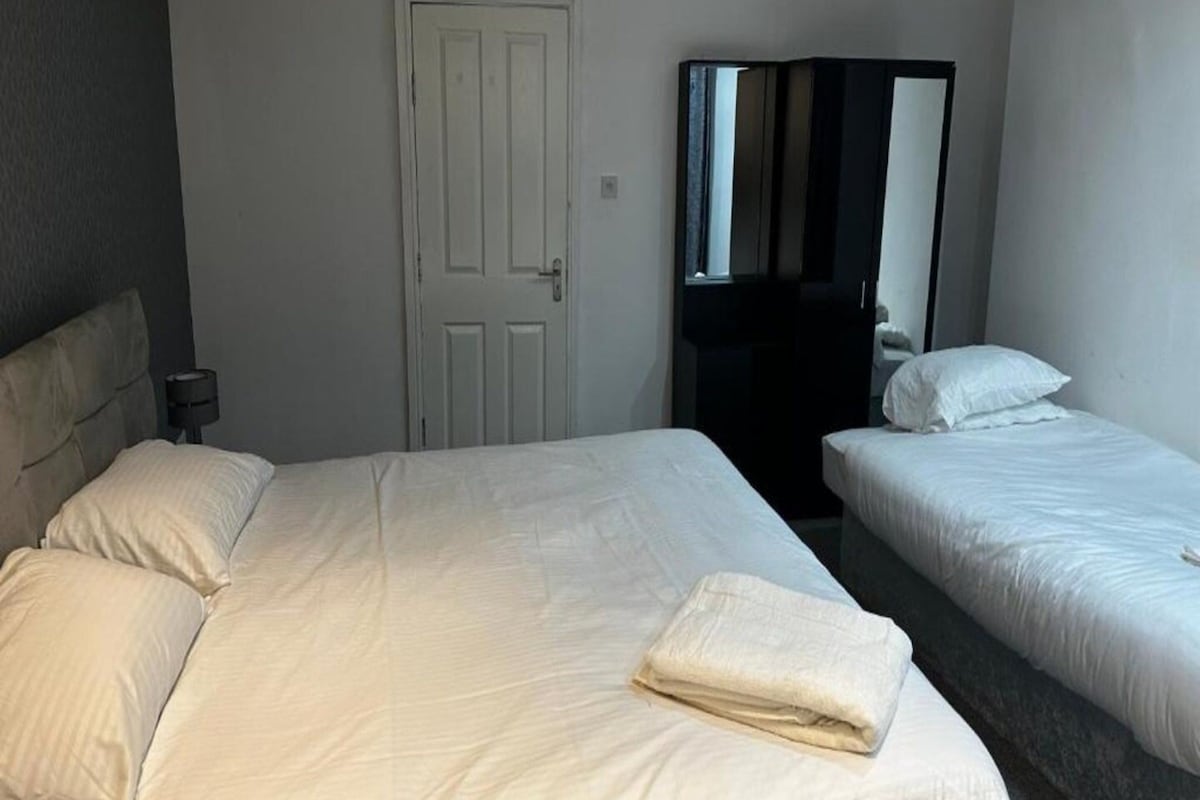 Ein Hotelzimmer mit zwei Betten, einer weißen Tür und einem Spiegel.