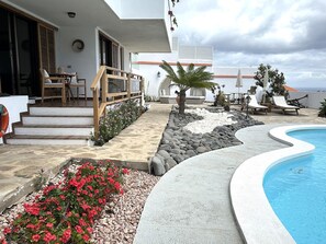 A pool area with a curved edge, a staircase leading to a deck, and outdoor seating. - Apartment in Radazul by the sea (El Rosario)
