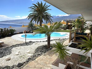 A pool area with a view of the sea and mountains, surrounded by rocks and plants. - Apartment in Radazul by the sea (El Rosario)
