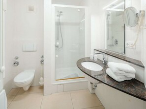 A bathroom with a toilet, a shower enclosure, a sink with a mirror, and a towel on the counter. - Holiday Apartment in Juist With Swimming Pool (Juist)
