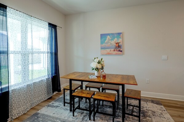 A dining area with a wooden table, benches, and a vase of flowers. - Walk to Beach! Windmark Family Home (Port St Joe)