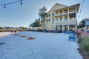 A beachside building with multiple balconies, outdoor seating, and a sandy area with beach chairs and tables. - Walk to Beach! Windmark Family Home (Port St Joe)