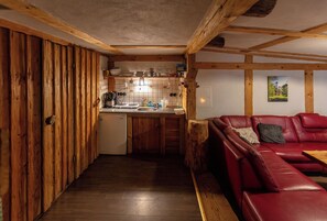 Eine kleine Küche mit Holdekor und ein rotes Ledersofa in rustikalem Ambiente.